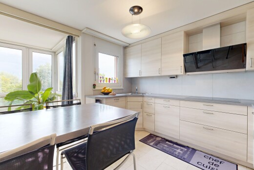kitchen featuring ventilation hood, hanging light fixtures, stainless steel countertops, light wood finish cabinets, and black electric stovetop