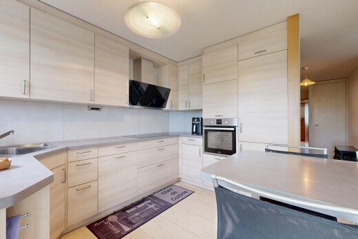 kitchen featuring stainless steel oven, light countertops, light wood finish cabinetry, and black electric stovetop