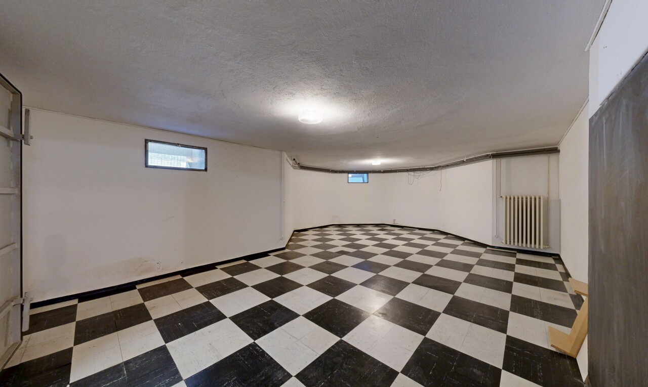 pièce vide avec radiateur, lumière naturelle, plafond texturé, sous-sol, et sol en vinyle