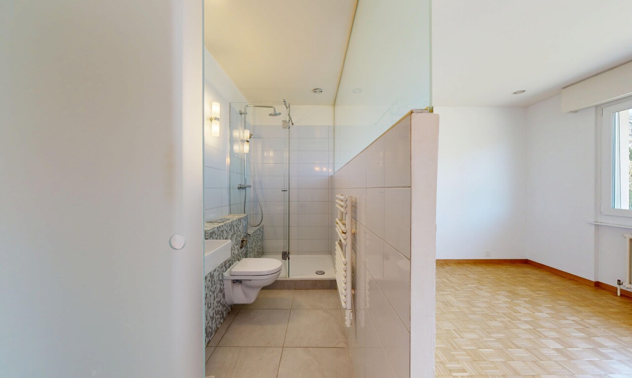 salle de bains avec cloison sèche, toilette, plinthes murales, douche, et salle de bain complète