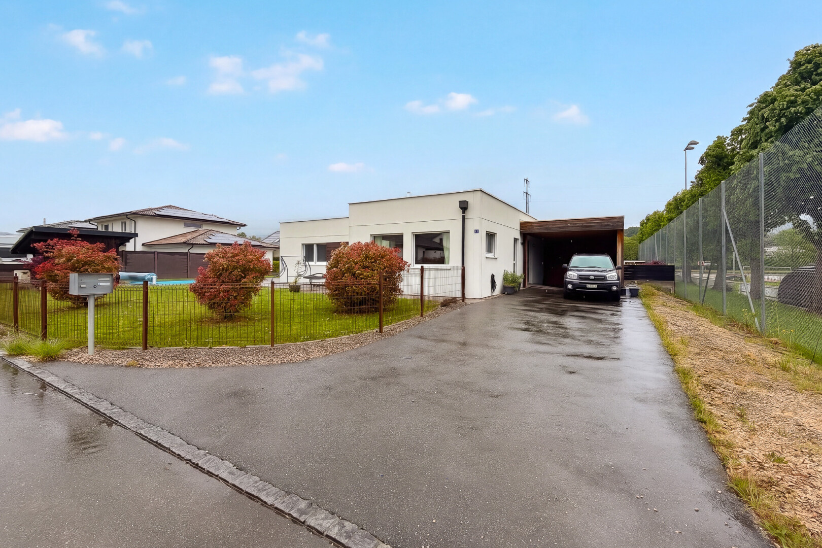außenansicht mit zaun, rasen, property visible, carport angeschlossen, und auffahrt