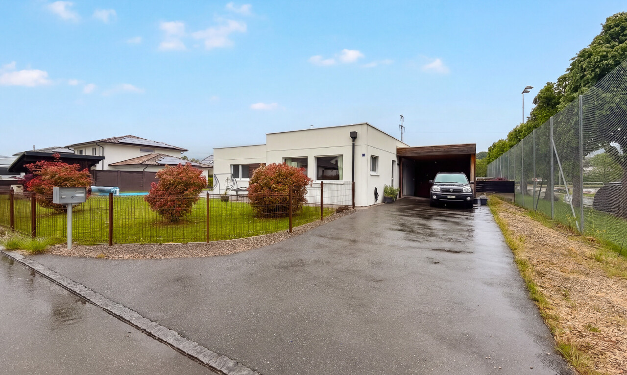 außenansicht mit zaun, rasen, property visible, carport angeschlossen, und auffahrt