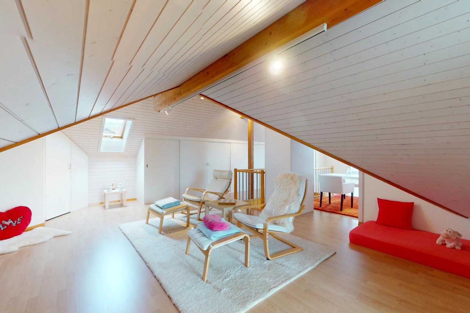 salon avec poutres apparentes, lumière naturelle, plafond voûté, plancher de bois, et lucarne