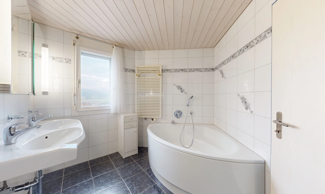 salle de bain avec radiateur, lumière naturelle, vasque, mur carrelé, et plafond de bois