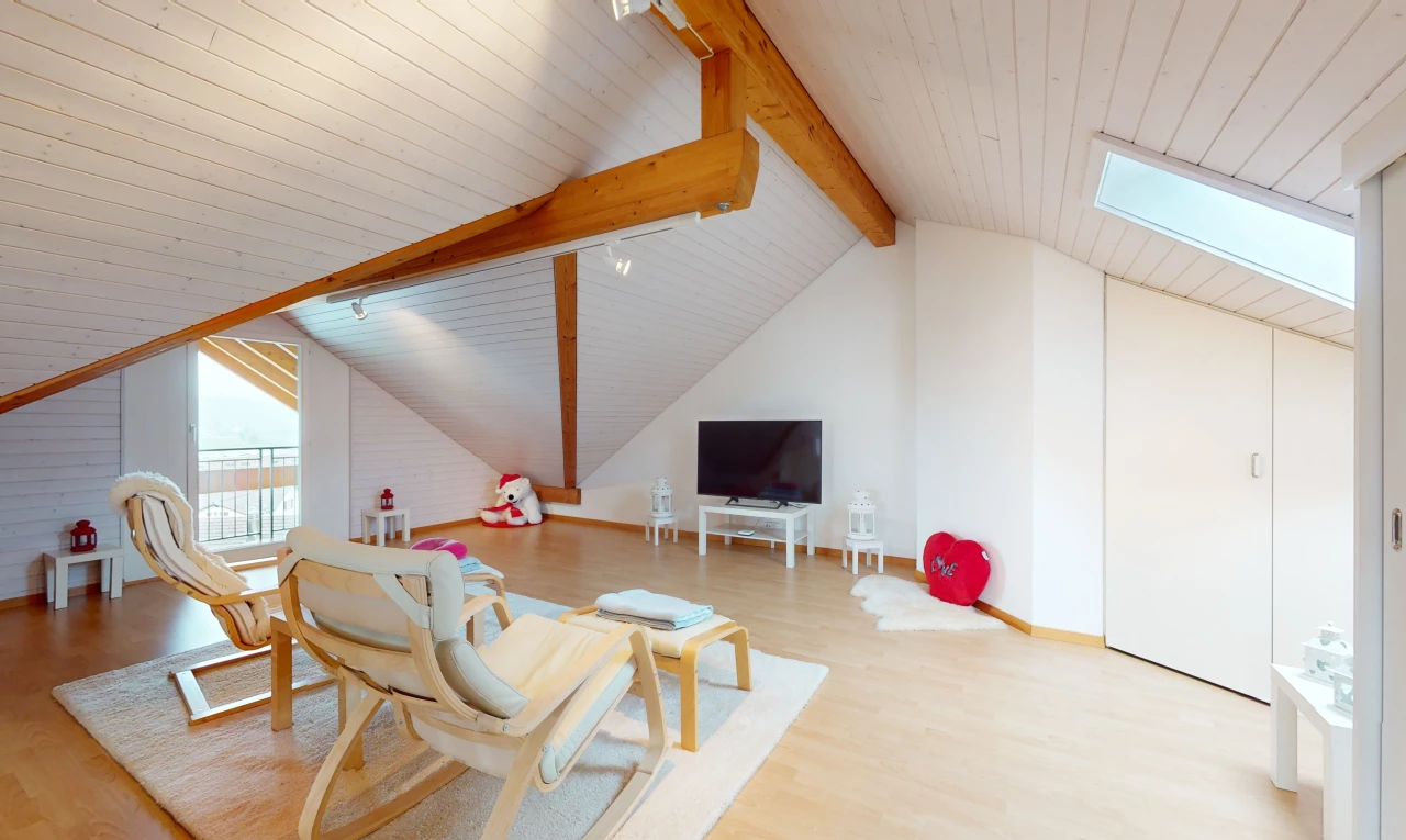 espace intérieur avec poutres apparentes, télévision, plancher de bois, plafond voûté, et éclairage sur rail
