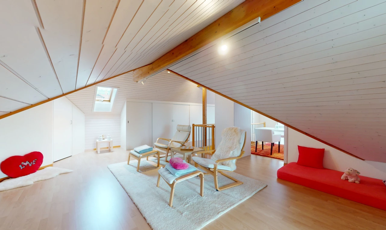 salon avec poutres apparentes, lumière naturelle, plafond voûté, plancher de bois, et lucarne