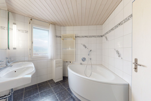 bad mit waschbecken, fliesenböden, holzdecke, heizheizeinheit und fliesenwänden