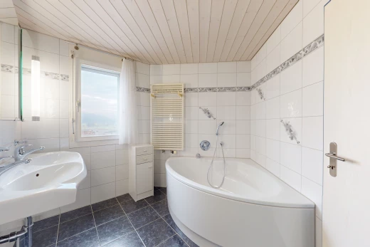 salle de bain avec radiateur, lumière naturelle, vasque, mur carrelé, et plafond de bois