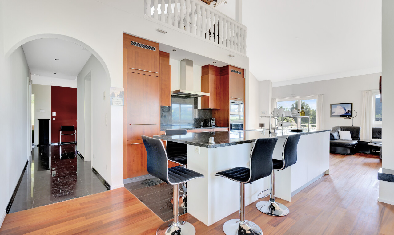 küche mit mittelbraune schränke, gewölbte gehwege, küchenbar, schränke mit flachen paneelen, und holzfußboden