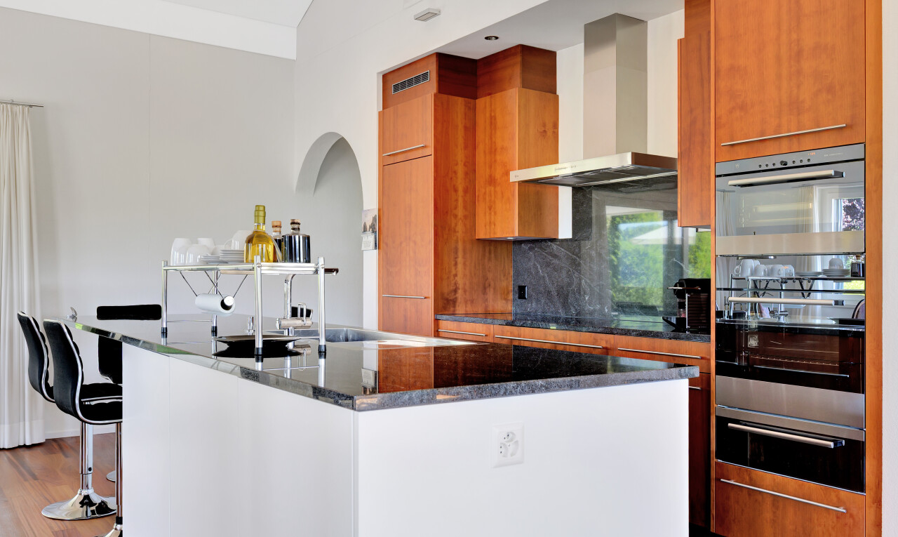 küche mit schränke mit flachen paneelen, kücheninsel, dunstabzugshaube, stein arbeitsplatten, und inside property