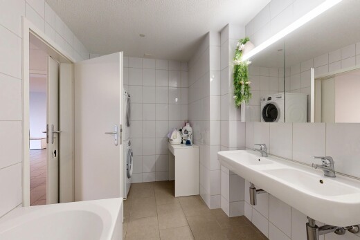 bathroom featuring tile walls, washer / clothes dryer, a tub to relax in, and light tile patterned floors