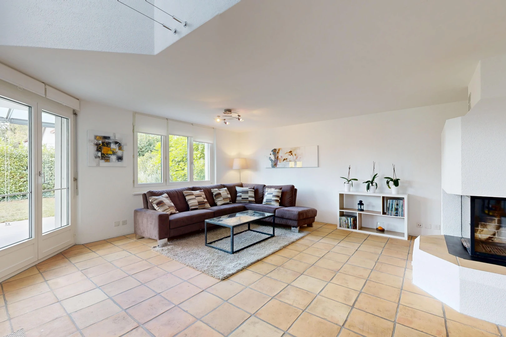 living room with access to exterior, a fireplace with raised hearth, and light tile patterned floors