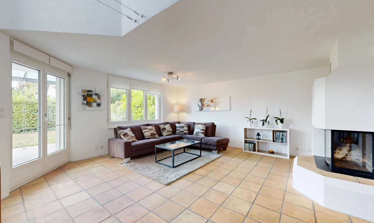 living room with access to exterior, a fireplace with raised hearth, and light tile patterned floors
