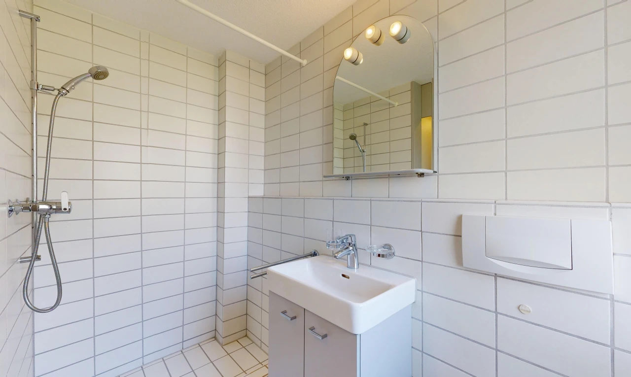 full bathroom with tiled shower, vanity, and tile walls