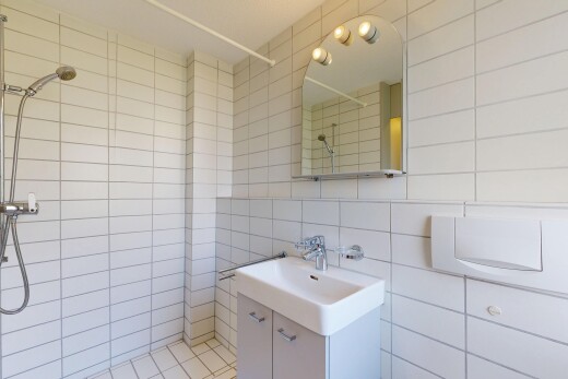 full bathroom with tiled shower, vanity, and tile walls