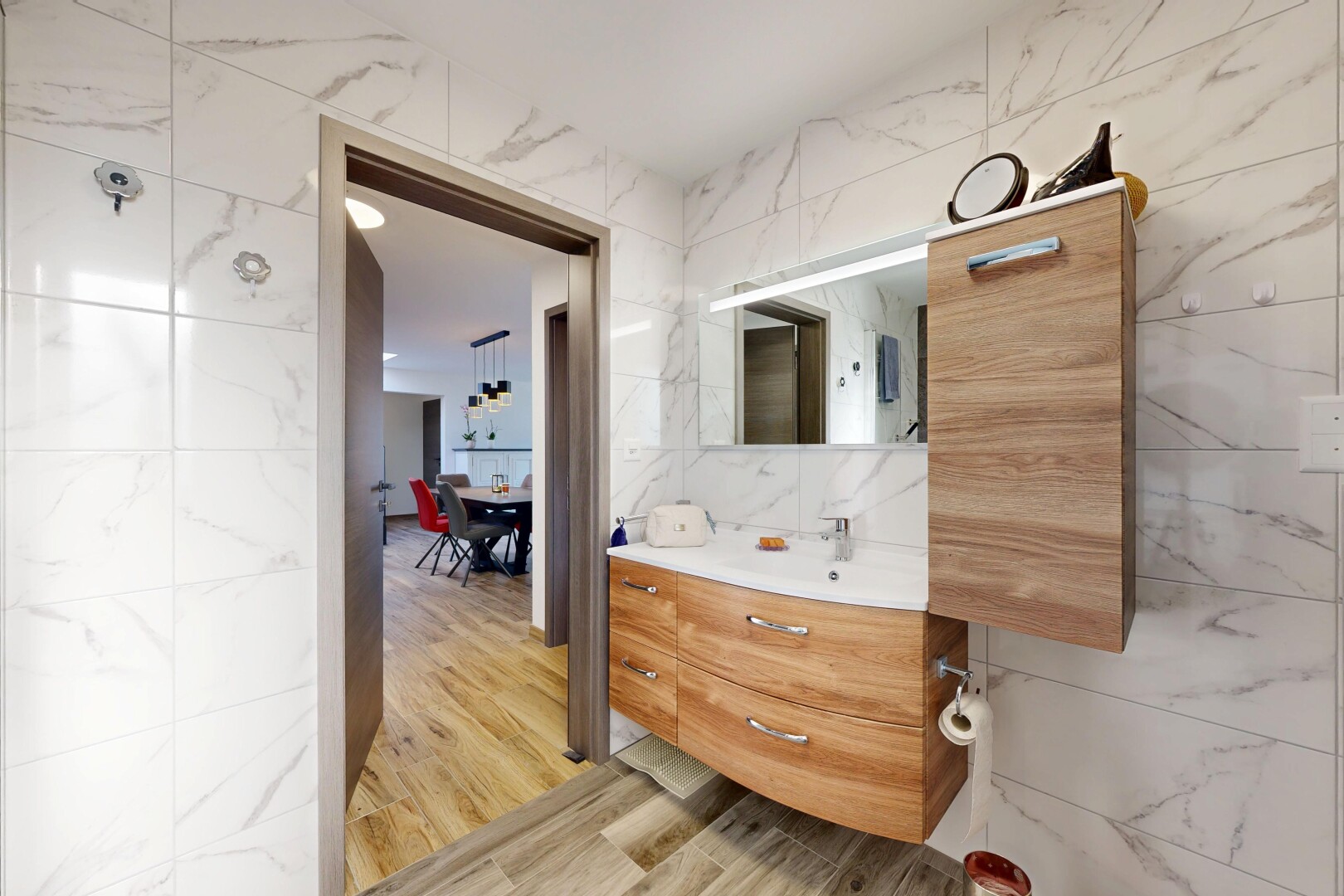 salle de bains avec tile wall, mur en carrelage, miroir, lavabo (ou coiffeuse selon le contexte), et wood finish floor