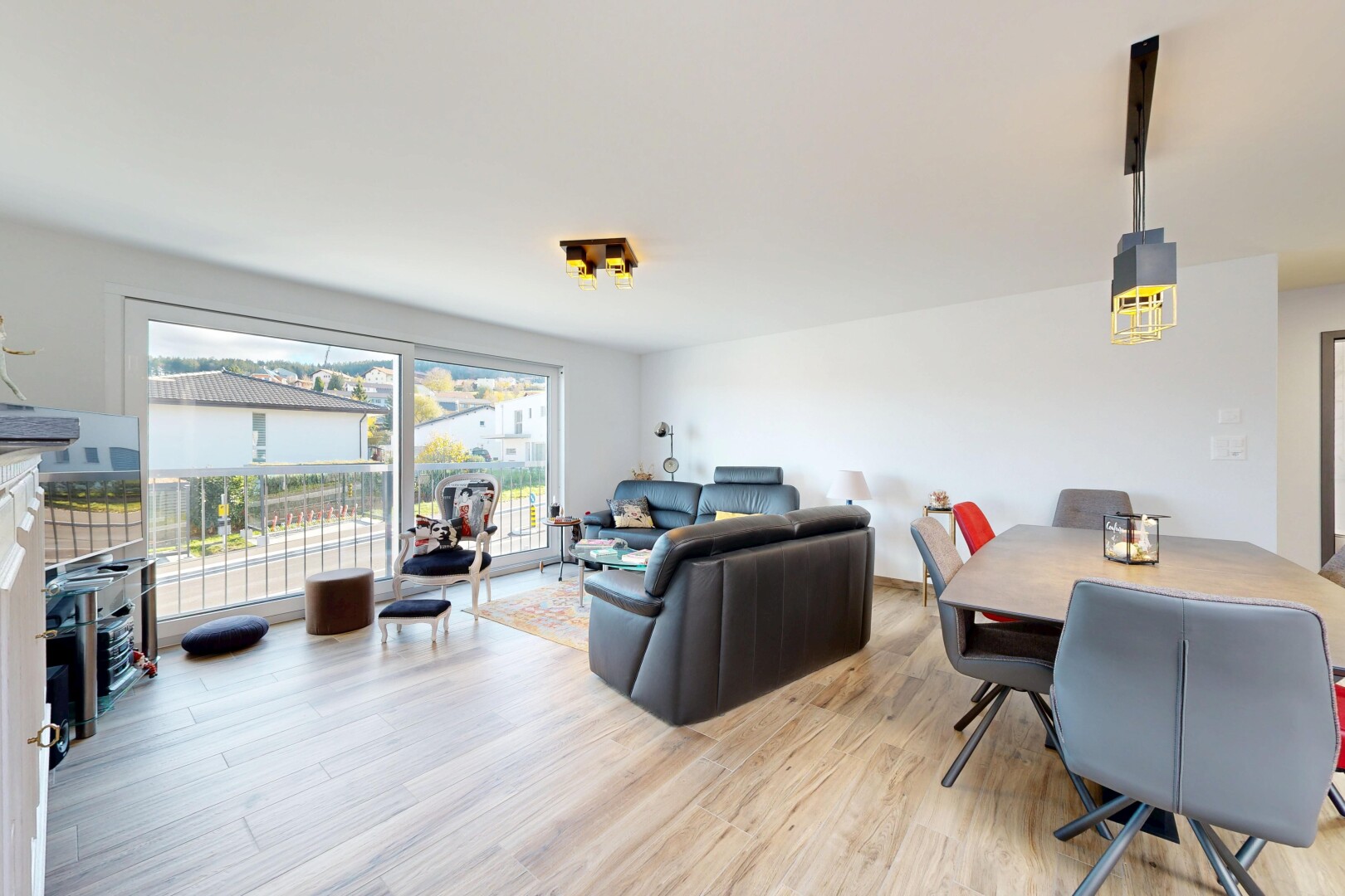 salon / salle à manger avec télévision, lumière naturelle, natural light, sol en finition bois, et wood finish floor