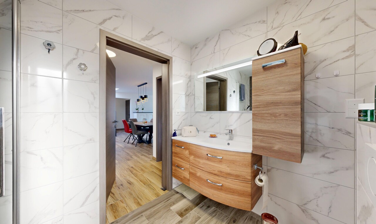 salle de bains avec tile wall, mur en carrelage, miroir, lavabo (ou coiffeuse selon le contexte), et wood finish floor