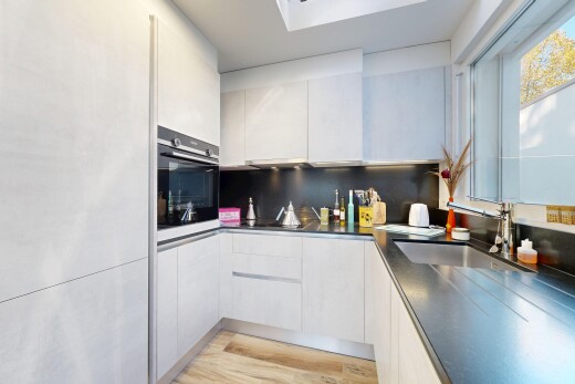 kitchen with oven, modern cabinets, light wood finished floors, white cabinetry, and backsplash