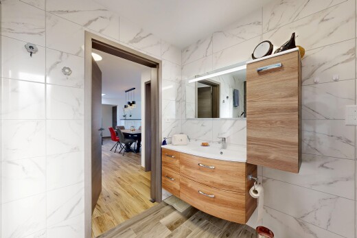 salle de bains avec tile wall, mur en carrelage, miroir, lavabo (ou coiffeuse selon le contexte), et wood finish floor
