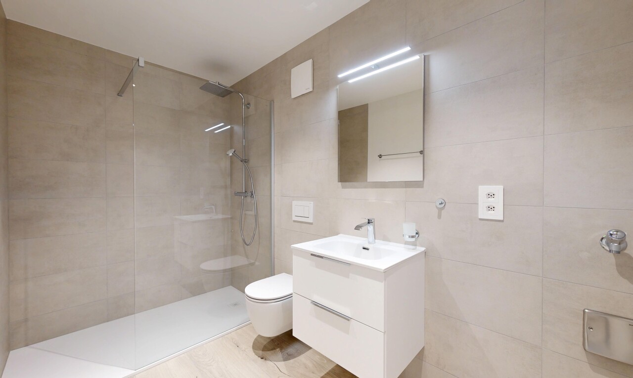 salle de bains avec miroir, lavabo (ou coiffeuse selon le contexte), salle de bain complète, douche, et mur en carrelage