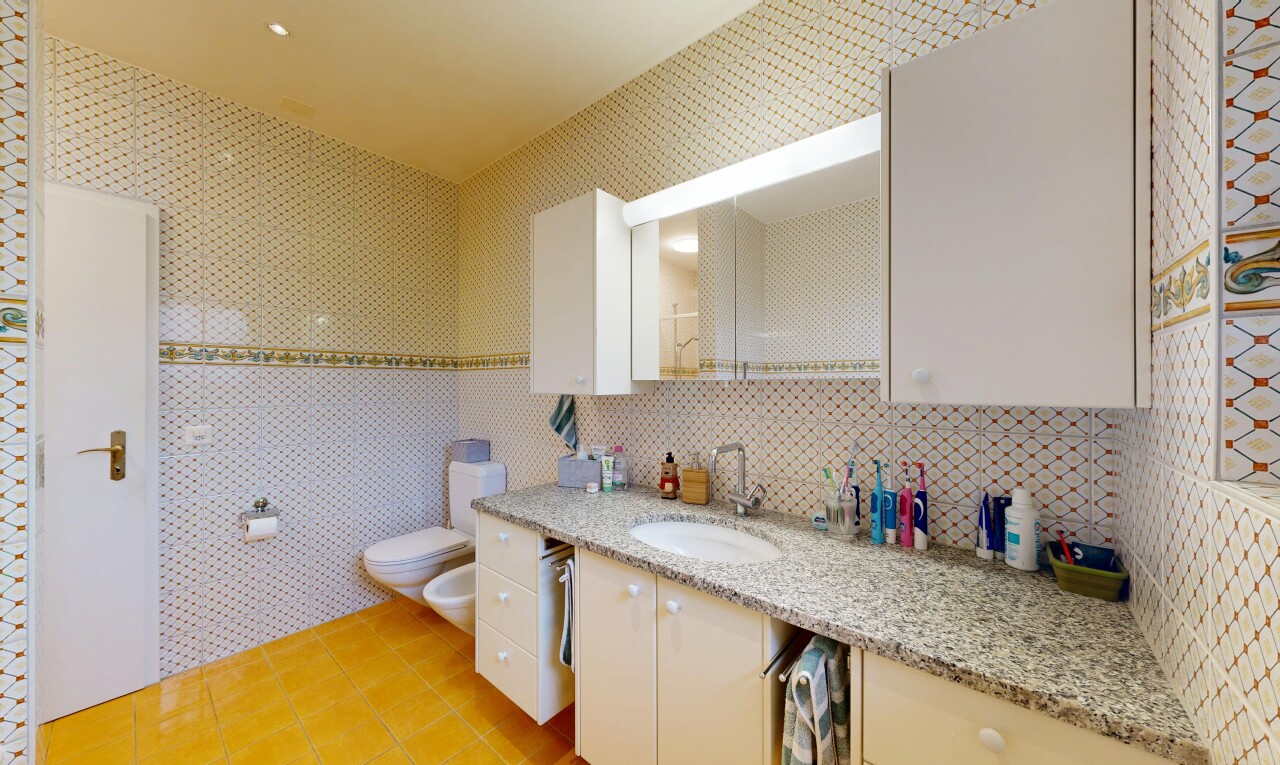 salle de bains avec sol en carrelage, tile floor, lavabo (ou coiffeuse selon le contexte), bidet, et miroir