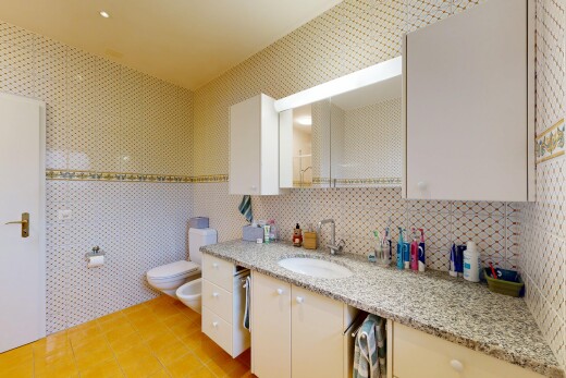 salle de bains avec sol en carrelage, tile floor, lavabo (ou coiffeuse selon le contexte), bidet, et miroir