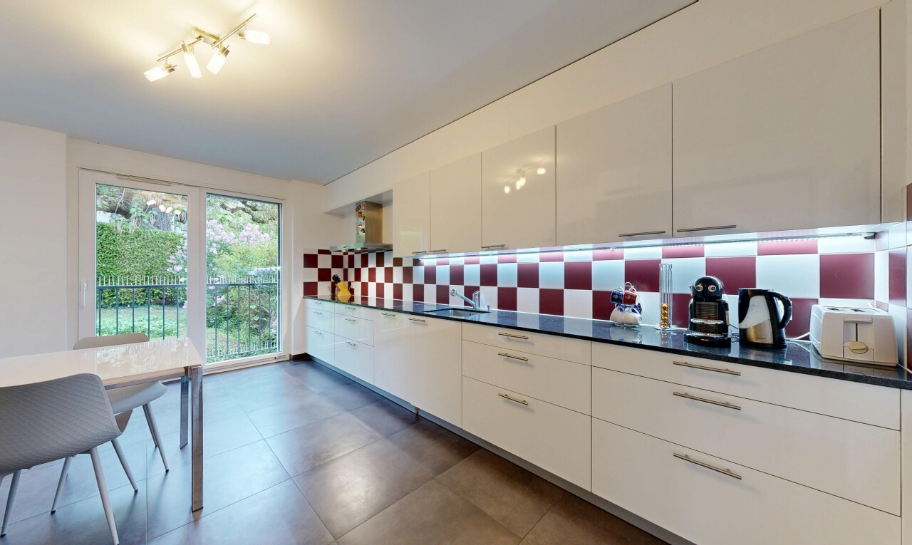 cuisine avec dark countertops, armoires blanches, white cabinets, dark floor, et lumière naturelle