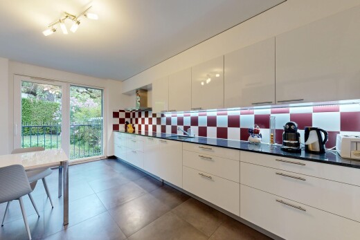 cuisine avec dark countertops, armoires blanches, white cabinets, dark floor, et lumière naturelle