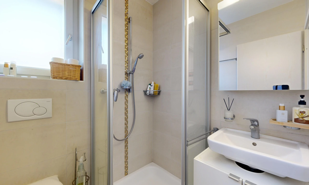 full bathroom with a stall shower, vanity, and tile walls