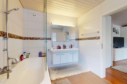 bad mit komplettes badezimmer, spiegel, doppelwaschtisch, fernseher, und kombiniertes bad / dusche