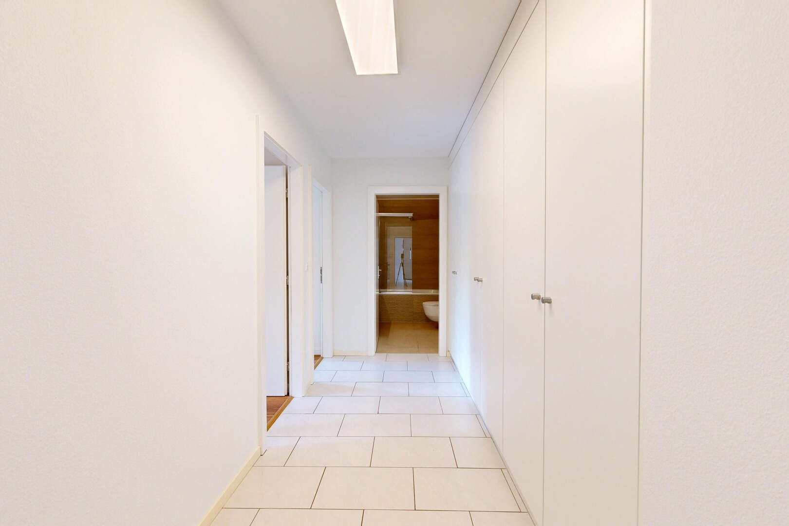 couloir avec light floor, tile floor, sol en carrelage, puits de lumière, et inside property