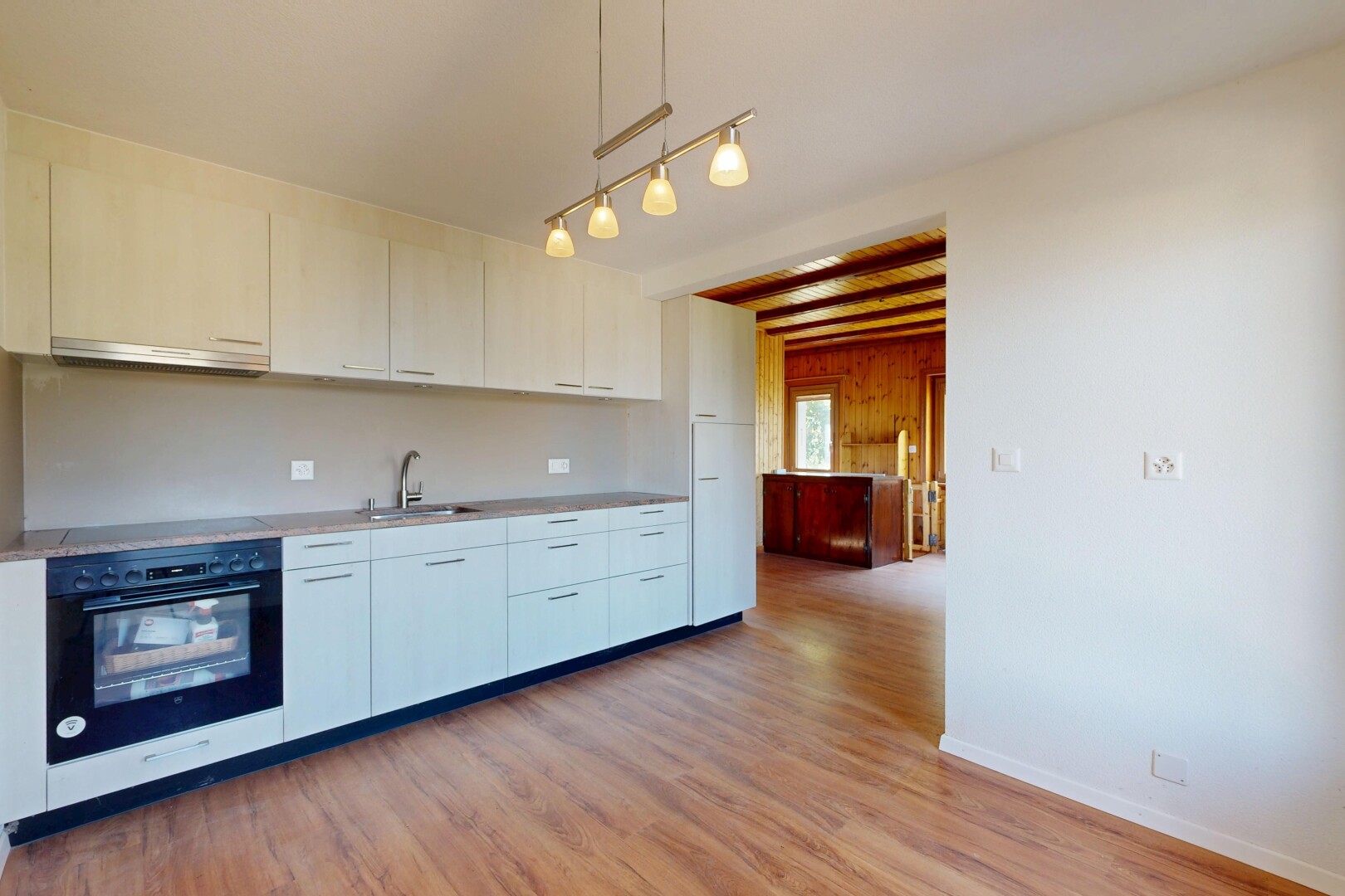 cuisine avec four, plans de travail, light countertops, inside property, et sol en finition bois