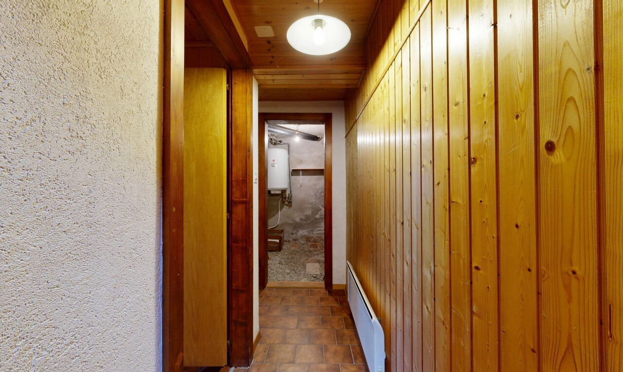 couloir avec radiateur à plinthe, sol en finition pierre, stone finish floor, chauffe-eau, et plafond en bois