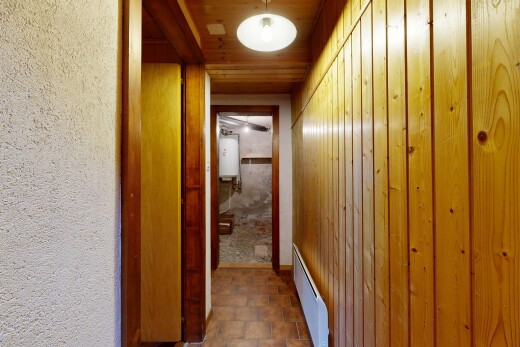 couloir avec radiateur à plinthe, sol en finition pierre, stone finish floor, chauffe-eau, et plafond en bois