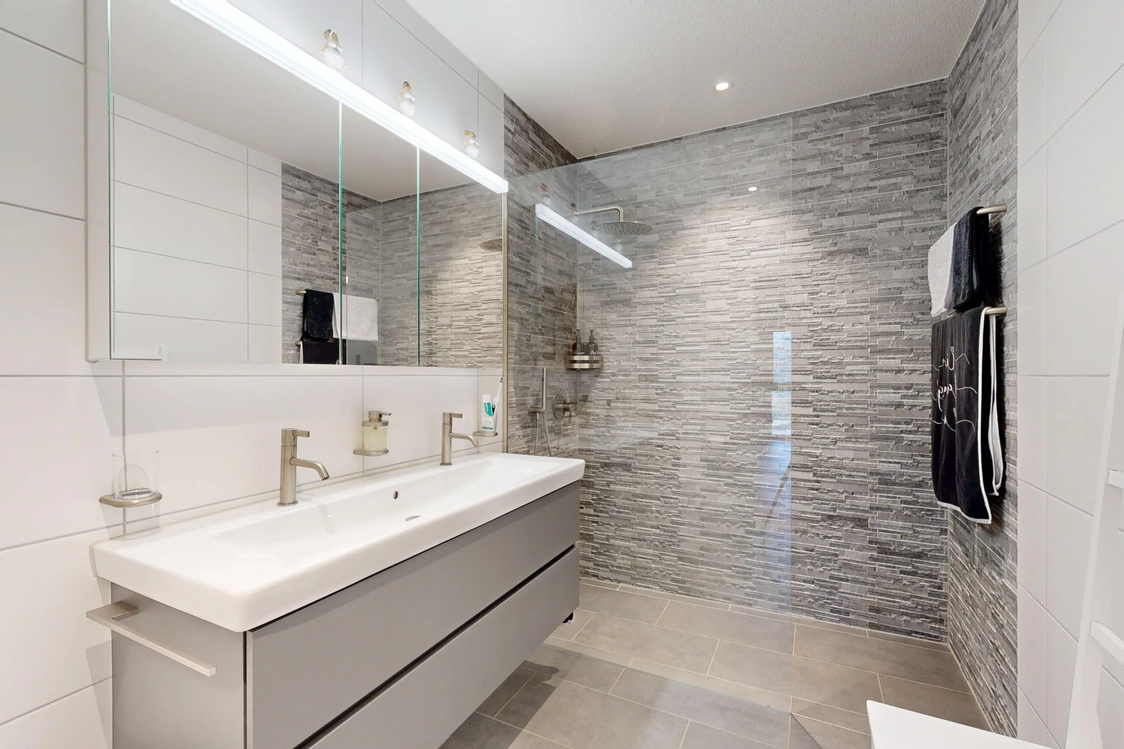 salle de bains avec douche, salle de bain complète, double vasque, light floor, et tile wall