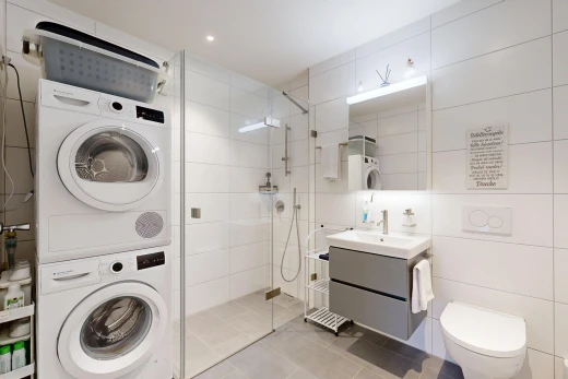 salle de bains avec lave-linge et sèche-linge superposés, douche, salle de bain complète, miroir, et lavabo (ou coiffeuse selon le contexte)