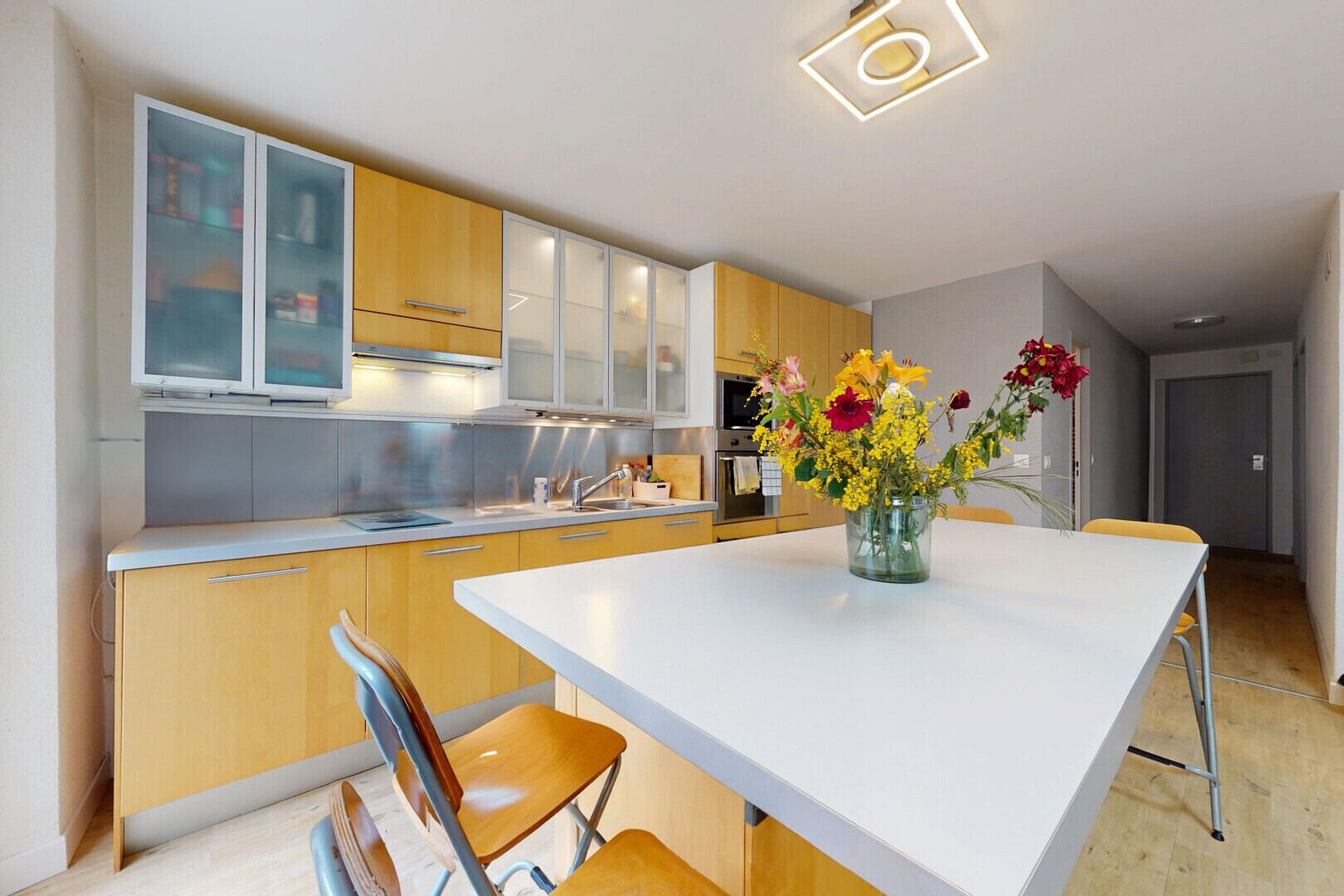 kitchen featuring a kitchen island, light countertops, a kitchen bar, glass insert cabinets, and modern cabinets