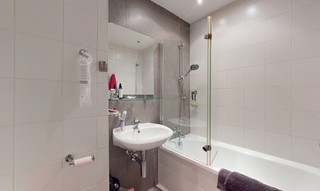 full bath with tiled shower / bath combo and tile walls