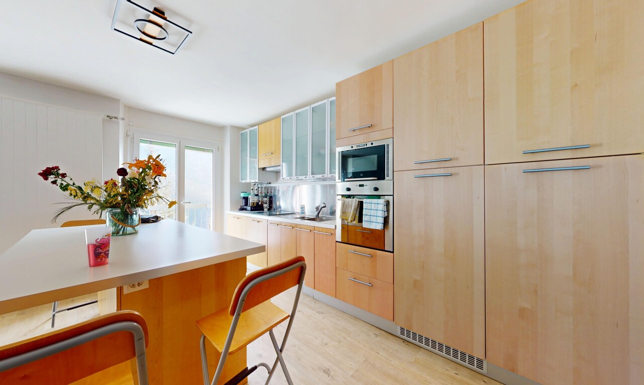 kitchen featuring light brown cabinets, stainless steel oven, light wood finished floors, light countertops, and glass insert cabinets