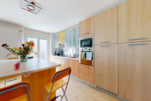kitchen featuring light brown cabinets, stainless steel oven, light wood finished floors, light countertops, and glass insert cabinets