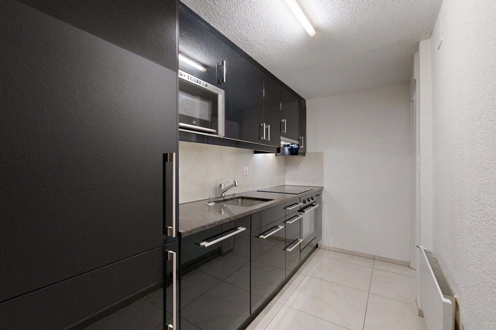 küche mit schwarze schränke, black cabinets, kühlschrank, light floor, und dark countertops