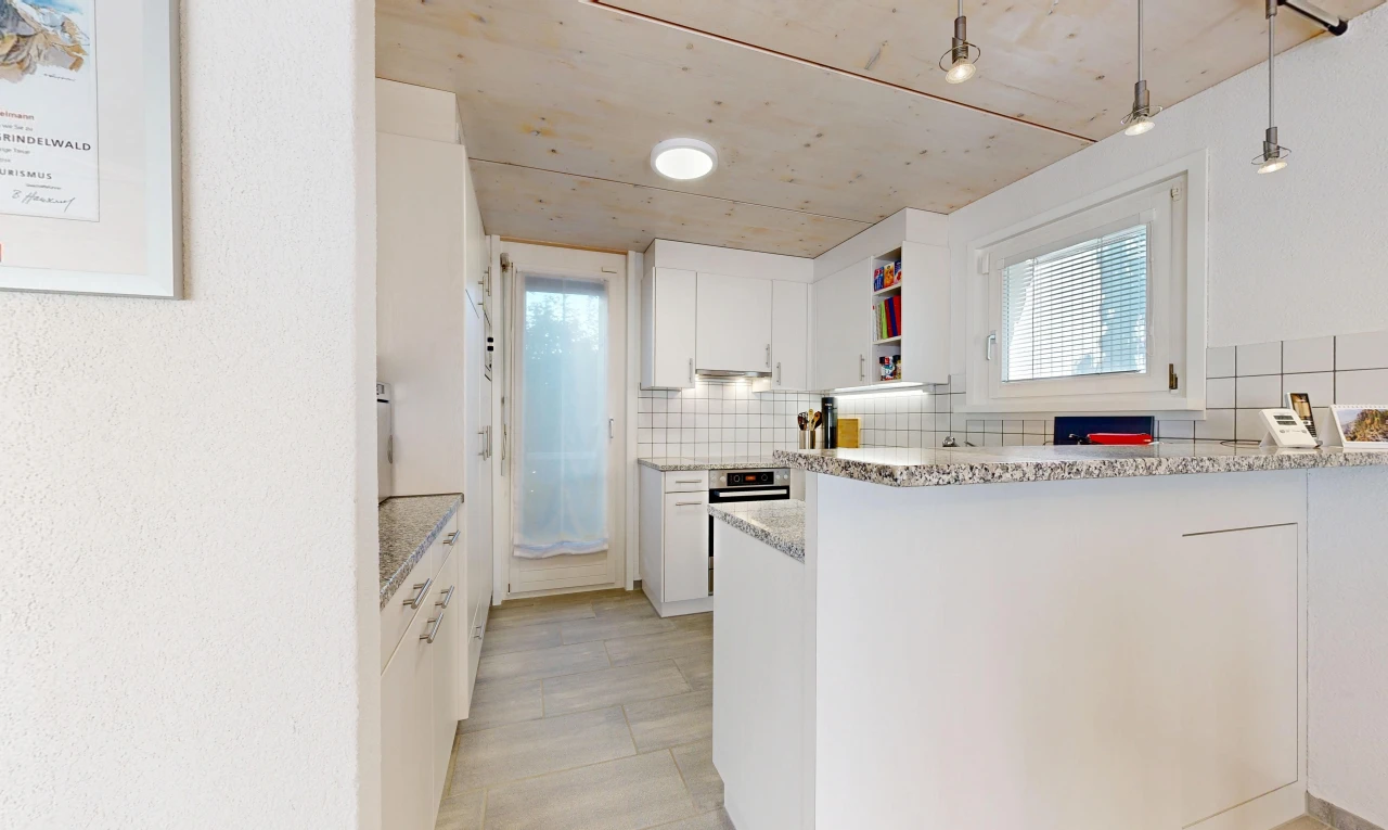 cuisine avec éclairage suspendu, light countertops, light floor, two heights countertops, et armoires blanches