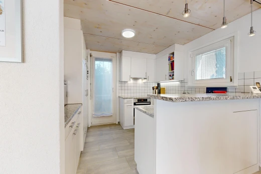 cuisine avec éclairage suspendu, light countertops, light floor, two heights countertops, et armoires blanches
