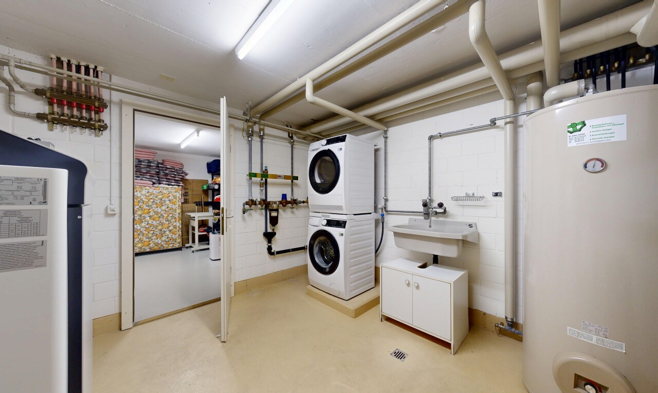 buanderie avec chauffe-eau, lave-linge et sèche-linge superposés, mur en blocs de béton, concrete block wall, et évier