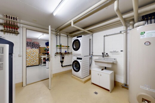 buanderie avec chauffe-eau, lave-linge et sèche-linge superposés, mur en blocs de béton, concrete block wall, et évier