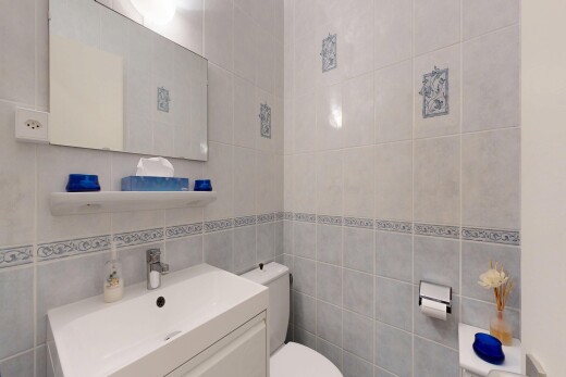 salle de bains avec miroir, lavabo (ou coiffeuse selon le contexte), toilette, mur en carrelage, et tile wall