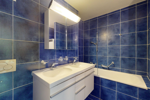 bad mit spiegel, schminktisch, doppelwaschbecken, fliesenwand, und kombiniertes bad / dusche