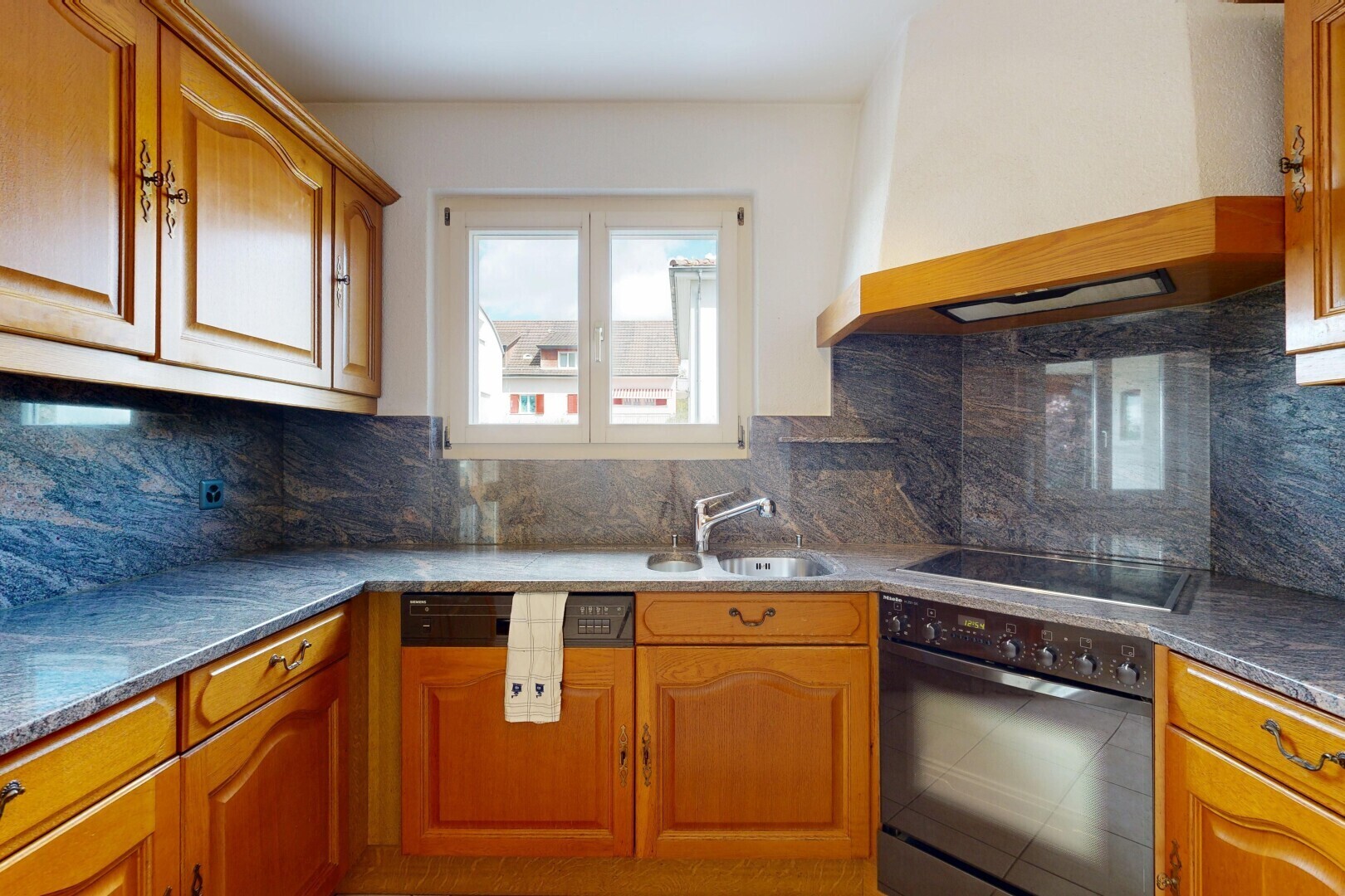 kitchen featuring custom range hood, black appliances, backsplash, and brown cabinets