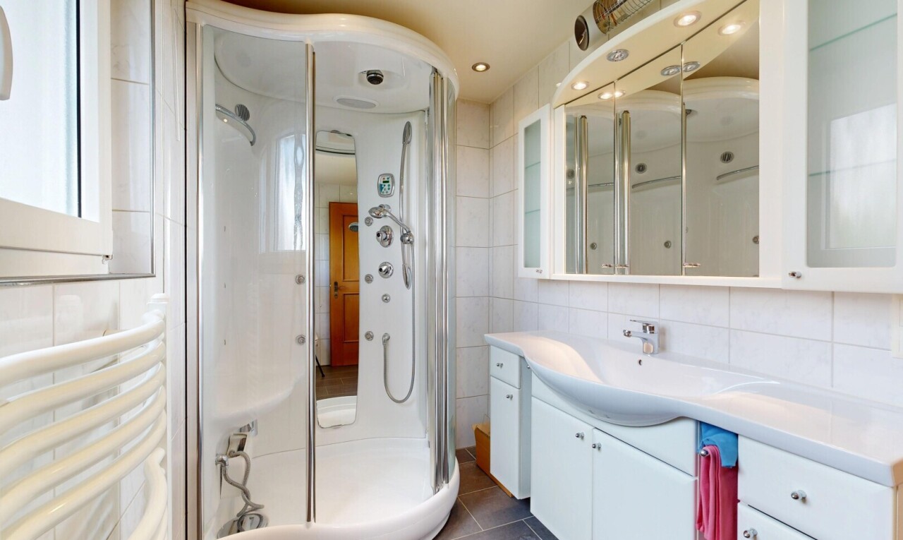 bathroom with a stall shower, vanity, tile walls, dark tile patterned flooring, and tasteful backsplash